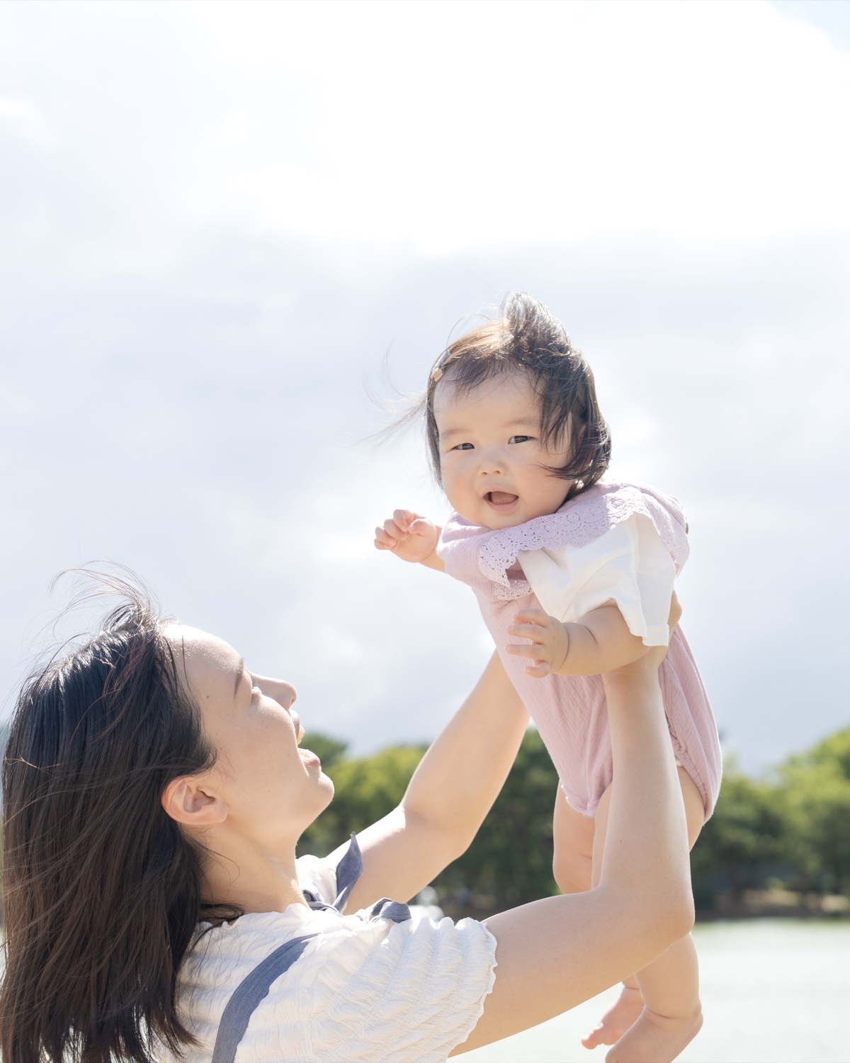 親子で赤ちゃんを抱き上げる写真